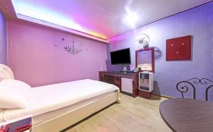 a bedroom with a bed and a table and a tv at Paldo Motel in Yeosu