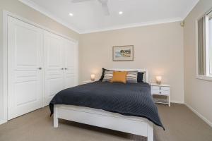 um quarto branco com uma cama e uma janela em A Perfect Stay - Sunrise on Shelly em East Ballina