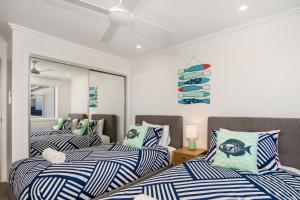two beds with blue and white striped sheets in a room at A Perfect Stay - Ocean Walk in Byron Bay
