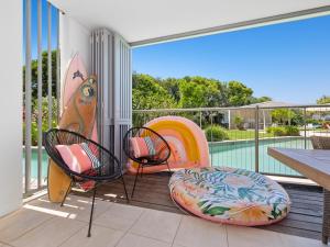 uma varanda com 2 cadeiras e uma piscina com pranchas de surf em Drift South Apartments by Kingscliff Accommodation em Casuarina