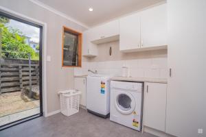 a white laundry room with a washer and dryer at Spacious with fabulous views overlooking the city in Hamilton
