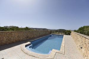 a swimming pool with a stone retaining wall and a stone staircase at Ta' Karkar Villa Bed and Breakfast in Xagħra