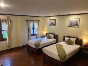 2 Betten in einem Zimmer mit Holzböden und Fenstern in der Unterkunft Luang Prabang Residence & Travel in Luang Prabang