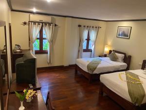 a hotel room with two beds and a television at Luang Prabang Residence & Travel in Luang Prabang