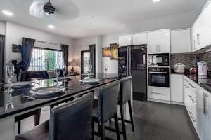 a kitchen with a large counter with chairs in it at Luxury Thai Style Pool Villa in downtown Pattaya, close to Walking Street in Pattaya South
