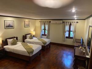 a hotel room with two beds and a television at Luang Prabang Residence & Travel in Luang Prabang