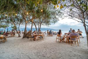 a group of people sitting at tables on the beach at Mowies Gili Air in Gili Islands
