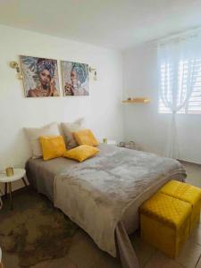 1 dormitorio con 1 cama grande con almohadas amarillas en La Maison Ti Pòlwizyèn plage à 3 mn à pieds, en Port-Louis