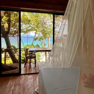 Amami Beachfront Villa with Private Beach في بويرتو غاليرا: غرفة نوم مطلة على المحيط من شرفة