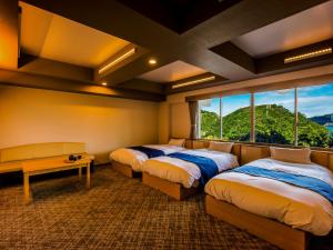 una camera con tre letti, un tavolo e finestre di Yukai Resort Premium Toba Saichoraku a Toba