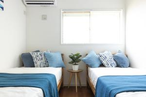two beds in a room with blue and white pillows at The Beach Front Miurakaigan - Vacation STAY 10780 in Miura