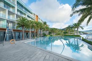 une piscine bordée de palmiers et un bâtiment dans l'établissement The Yun Resort Shenzhen Longcheer, à Shenzhen