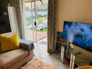 a living room with a couch and a flat screen tv at Terry’s Cozy cottage in Germiston