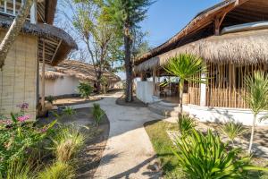 un edificio resort con techo de paja y patio en Mowies Gili Air, en Gili Air