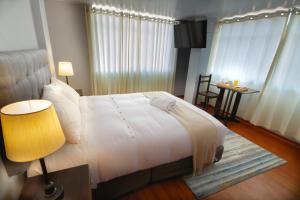 1 dormitorio con 1 cama, 1 mesa y 1 lámpara en Casa Hotel Lago Titicaca, en Puno