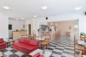 a restaurant with red chairs and tables and a counter at Erato Hotel in Agia Marina Aegina