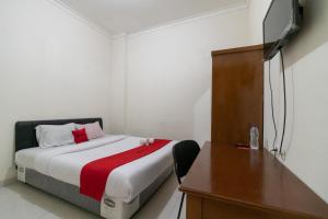1 dormitorio con 1 cama con escritorio y vestidor en RedDoorz near Universitas Esa Unggul Bekasi Harapan Indah, en Bekasi