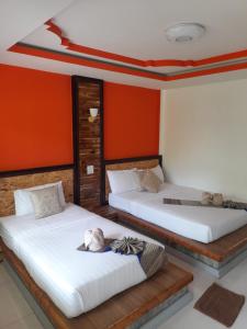 two beds in a room with red walls at Lanta Emerald Bungalow in Ko Lanta