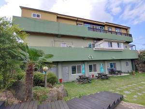 a large building with a balcony and picnic tables at Jeju Oreum Pension in Jeju