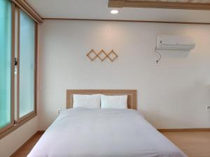 a bedroom with a white bed and a window at Jeju Oreum Pension in Jeju