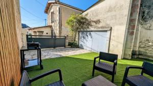 a backyard with a lawn with chairs and a fence at La Maison d'Elise, 3 chambres, maison de caractère in Plassac