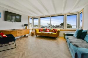 a living room with a couch and a tv and windows at Seaside Luxury Escape in Aberdour