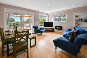 a living room with two blue couches and a table at Blacksand sea view cottage in Aberdour