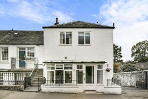 a white house with a porch and a balcony at Blacksand sea view cottage in Aberdour
