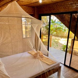 Amami Beachfront Villa with Private Beach في بويرتو غاليرا: شبكة على سرير في غرفة مع نوافذ