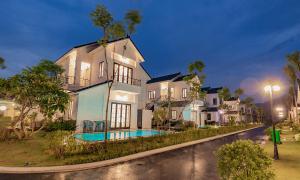 a large white house with a pool in front of it at Vườn Vua Resort & Villas in Ðồng Phú