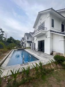 a white house with a swimming pool in front of it at Vườn Vua Resort & Villas in Ðồng Phú