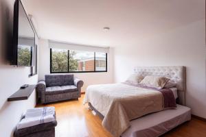 a bedroom with a bed and a chair and a window at Casa con Jacuzzi en Bogota (Weed Friendly) in Bogotá