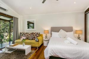 a bedroom with a bed and a yellow couch at A Perfect Stay - Blue Bliss House and Studios in Byron Bay