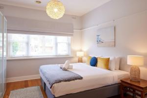 a bedroom with a large bed and two windows at Boutique Stays - Mordi Beach House in Mordialloc