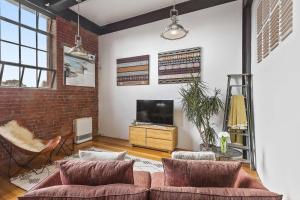 uma sala de estar com um sofá e uma televisão de ecrã plano em Boutique Stays - Loft on Rose em Melbourne