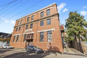 un edificio de ladrillo con un coche aparcado delante de él en Boutique Stays - Loft on Rose, en Melbourne