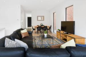 a living room with a black leather couch and a television at Boutique Stays - Murrumbeena Place 1 in Carnegie