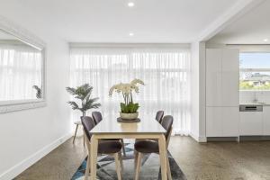 a white dining room with a table and chairs at Boutique Stays - Brighton By Sea in Melbourne