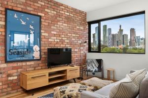 een woonkamer met een bakstenen muur en een tv bij Boutique Stays - Highviews in Melbourne