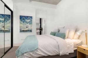 een slaapkamer met een groot wit bed met blauwe kussens bij Boutique Stays - Highviews in Melbourne