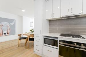 a kitchen with white cabinets and a dining room table at Boutique Stays - Hampton Lookout in Melbourne