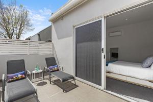 a balcony with a bed and two chairs and a bedroom at Boutique Stays - Port Haven in Melbourne