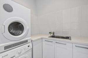 a white kitchen with a sink and a washing machine at Boutique Stays - Port Haven in Melbourne