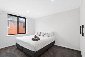 a white bedroom with a bed and a window at Boutique Stays - Ace's Place in Melbourne