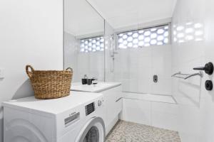 a white bathroom with a washing machine and a sink at Boutique Stays - Ace's Place in Melbourne