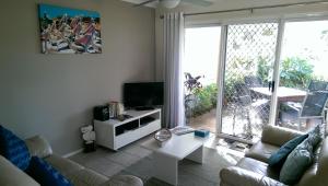 a living room with a couch and a tv at Sails Lifestyle Resort in Peregian Beach