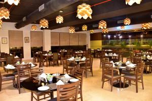 The Fern Residency, Vadgaon - Talegaon, Pune في بيون: غرفة طعام بها طاولات وكراسي وثريات