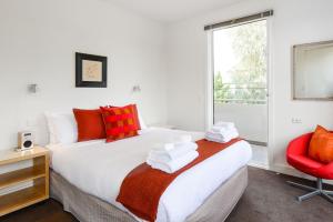 1 dormitorio con 1 cama grande y 1 silla roja en Boutique Stays - Maple on Kent, en Melbourne