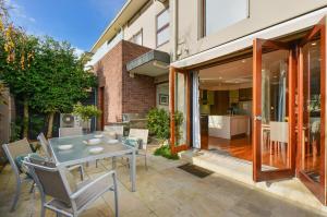 un patio con mesa y sillas y un edificio en Boutique Stays - Maple on Kent, en Melbourne