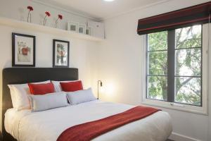 a white bedroom with a large bed with red pillows at Boutique Stays - Wellington Mews in Melbourne